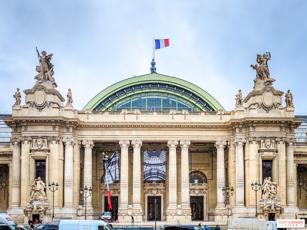 Vue de la façade ornée de la Gare de Lyon, avec des sculptures majestueuses et le drapeau français flotant au sommet.