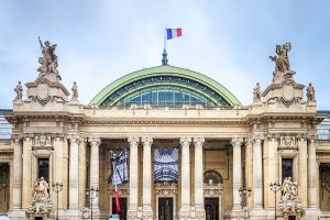 Vue de la façade ornée de la Gare de Lyon, avec des sculptures majestueuses et le drapeau français flotant au sommet.