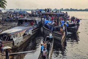 Vie portuaire animée:::Scène d'une multitude de personnes sur des bateaux au bord de l'eau, avec des marchandises et des activités commerciales sur les quais.