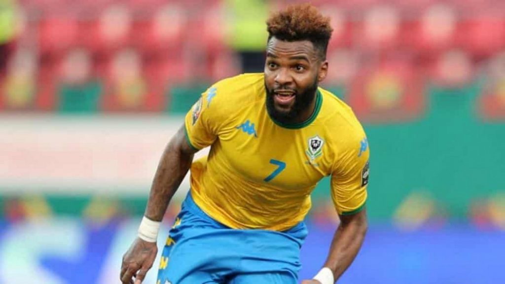 Un joueur de football portant un maillot jaune et bleu, courant avec enthousiasme sur le terrain.