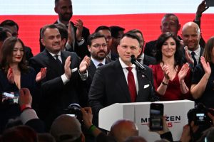 Un candidat politique s'exprime devant un public applaudi, entouré de soutien lors d'un événement mémorable.