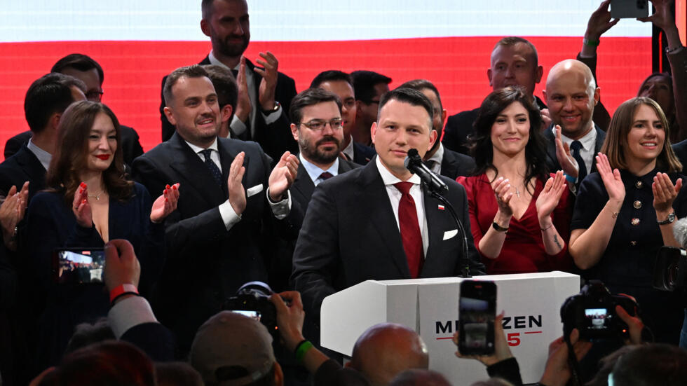 Un candidat politique s'exprime devant un public applaudi, entouré de soutien lors d'un événement mémorable.