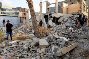 Un homme marche à travers les décombres d'immeubles détruits, tandis que d'autres inspectent les dégâts dans un quartier touché.