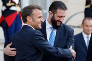 Deux hommes se serrent dans une accolade amicale lors d'un événement officiel, avec des membres des forces de l'ordre en arrière-plan.