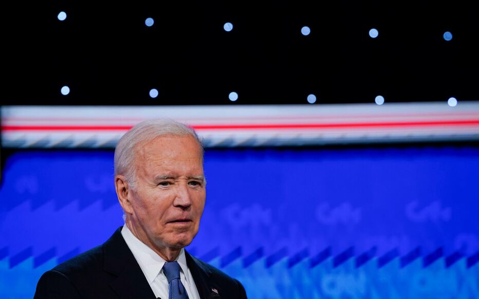 Joe Biden s'exprime lors d'un débat avec un éclairage de scène et un fond coloré.