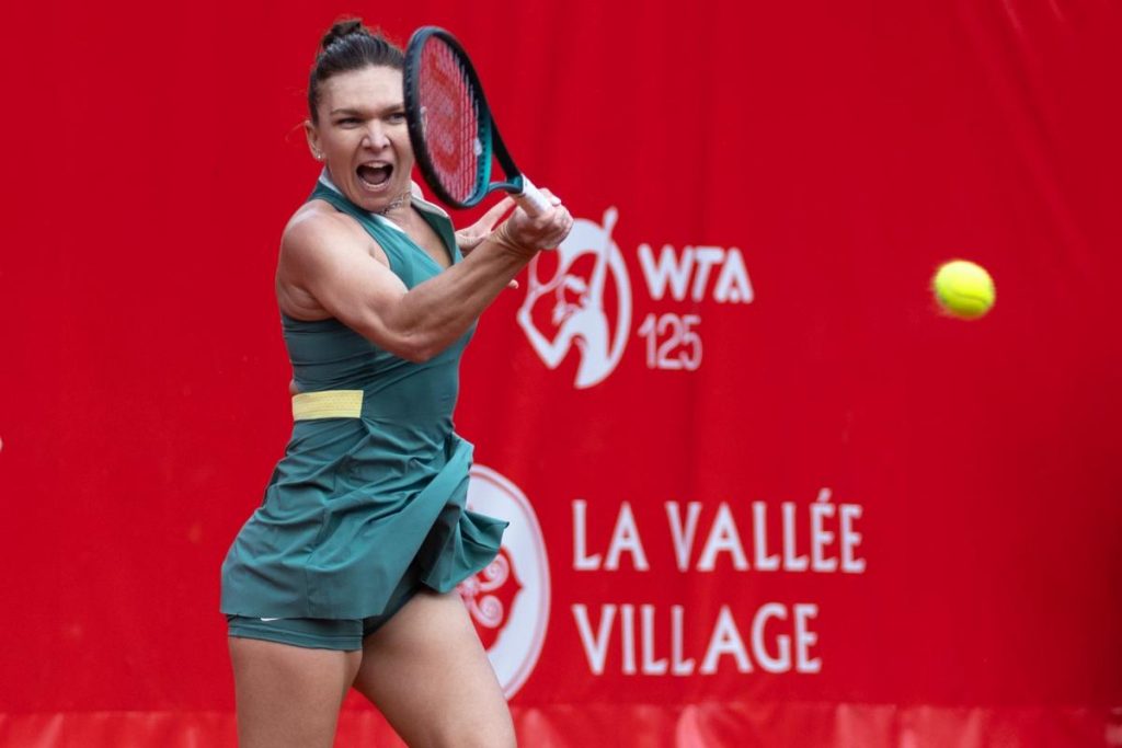 Joueuse de tennis frappant la balle avec intensité sur un court rouge du tournoi WTA 125.