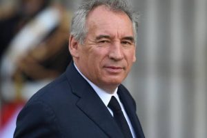 Portrait d'un homme en costume:::Un homme au cheveux grisonnants, portant un costume noir, regarde directement vers l'objectif avec un air sérieux.